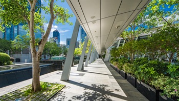 Covered walkways are bordered with trees and shrubs and is aligned with the adjacent linear water feature.